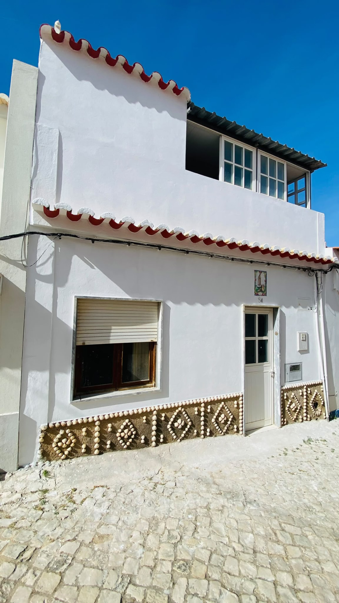 Casa de aldeia branca em rua de calçada